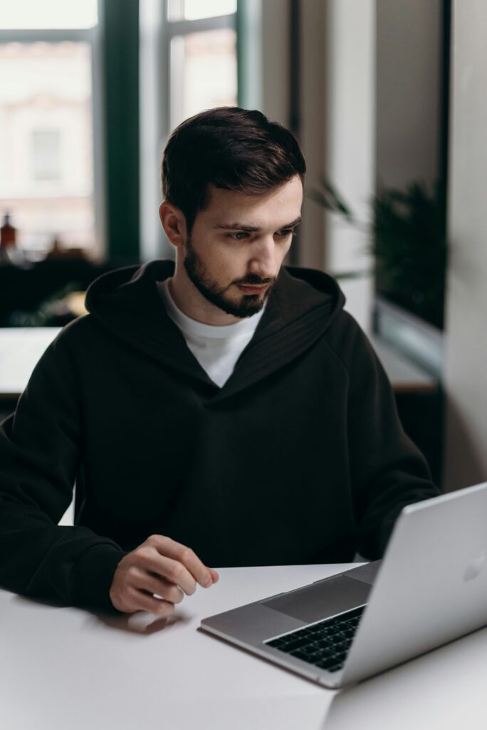 A focused young man using a laptop at a desk in a stylish home office setting.